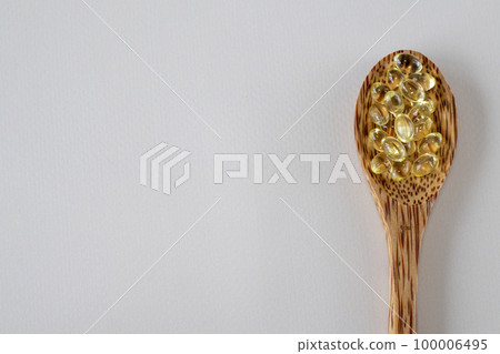 Sunny vitamin D3 supplement capsules in a wooden spoon beige background. Blank space for copying or text. Pills, medications and vitamins. Close-up. Sunny vitamin D3 supplement capsules in a wooden spoon beige background. Blank space for copying or text. Pills, medications and vitamins. Close-up. 100006495