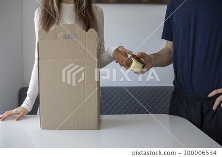 Man hands a woman a packed canned meal to put in a charity box. This gesture demonstrates an act of kindness and generosity The image symbolizes the importance of helping others and the power of small Man hands a woman a packed canned meal to put in a charity box. This gesture demonstrates an act of kindness and generosity The image symbolizes the importance of helping others and the power of small 100006534