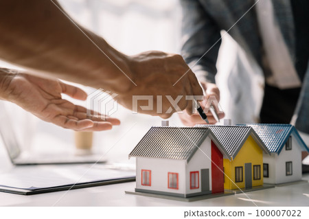 Buying a home or insurance deal, an insurance agent pointing a pen to those interested in renting a house, a contract, signing an Home buying agreement in office Buying a home or insurance deal, an insurance agent pointing a pen to those interested in renting a house, a contract, signing an Home buying agreement in office 100007022