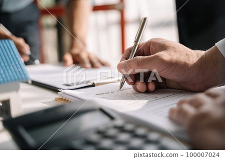 Buying a home or insurance deal, an insurance agent pointing a pen to those interested in renting a house, a contract, signing an Home buying agreement in office 100007024