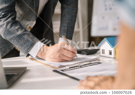 Buying a home or insurance deal, an insurance agent pointing a pen to those interested in renting a house, a contract, signing an Home buying agreement in office Buying a home or insurance deal, an insurance agent pointing a pen to those interested in renting a house, a contract, signing an Home buying agreement in office 100007026