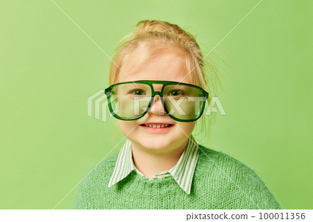 Happy smiling cute kid, little girl in fashionable look clothes and sunglasses posing over light green background. Spring fashion collection, happiness, ad concept Happy smiling cute kid, little girl in fashionable look clothes and sunglasses posing over light green background. Spring fashion collection, happiness, ad concept 100011356