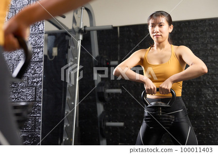 年輕女子用壺鈴訓練 100011403