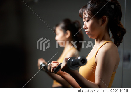 Young woman training with barbell shaft Young woman training with barbell shaft 100011426