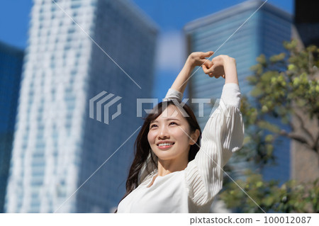 A young woman stretching with the blue sky in the background A young woman stretching with the blue sky in the background 100012087