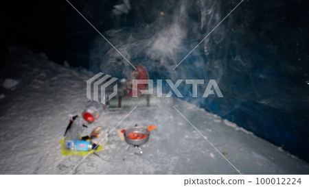 A guy cooks food on gas inside an ice cave. 100012224