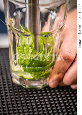 Bartender crushes mint and lime Bartender crushes mint and lime 100012442