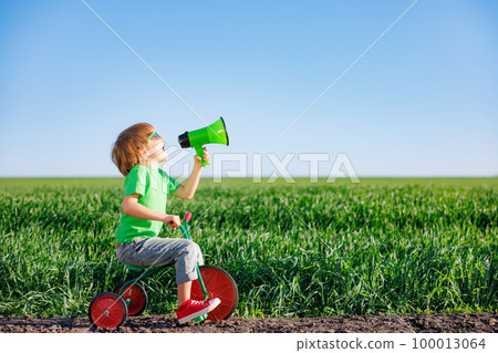 Child shouting through loudspeaker against blue summer sky 100013064