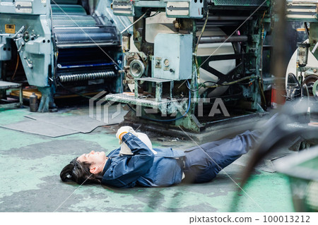 A worker lying down in a factory A worker lying down in a factory 100013212