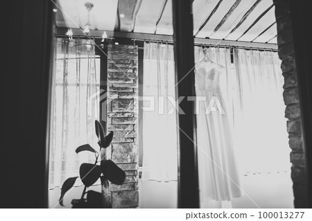 The perfect wedding dress with a full skirt on a hanger in the room of the bride 100013277