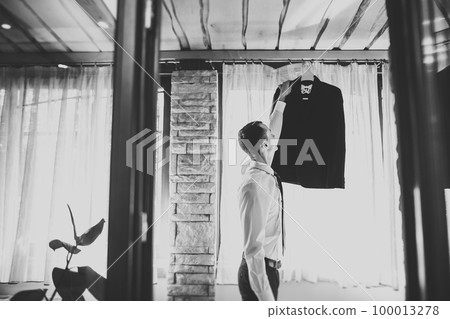 Grooms morning preparation. Handsome man getting dressed and preparing for the wedding Grooms morning preparation. Handsome man getting dressed and preparing for the wedding 100013278