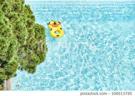 Man relax on inflatable rubber rings in swimming pool with clear blue water. Fun activities in water park at summer resort upper view Man relax on inflatable rubber rings in swimming pool with clear blue water. Fun activities in water park at summer resort upper view 100013780