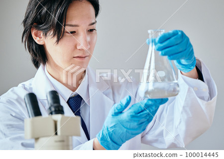 一個穿白大褂的年輕人在做實驗 一個穿白大褂的年輕人在做實驗 100014445