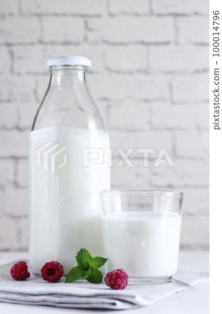 Organic probiotic milk kefir drink or yogurt in glass containers, with raspberry, on the white grey background. Gut health. Probiotic cold fermented dairy drink. Trendy food and drink. Copy space Organic probiotic milk kefir drink or yogurt in glass containers, with raspberry, on the white grey background. Gut health. Probiotic cold fermented dairy drink. Trendy food and drink. Copy space 100014796