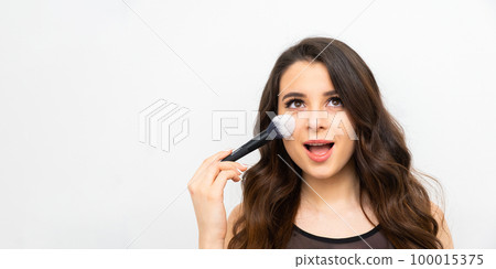 Portrait of a surprised woman applying face powder on the banner with copy space. Portrait of a surprised woman applying face powder on the banner with copy space. 100015375