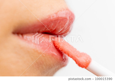 Makeup artist applying lip gloss on the white background. Makeup artist applying lip gloss on the white background. 100015390