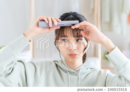 young woman doing hair irons 100015918