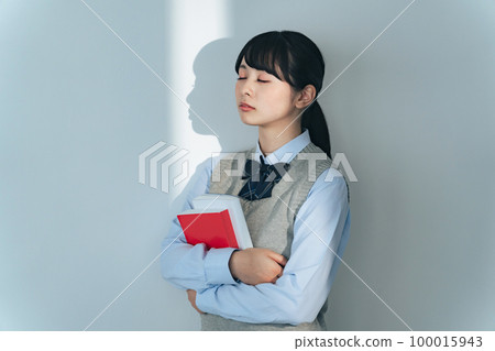 Female student holding a book and closing her eyes Female student holding a book and closing her eyes 100015943