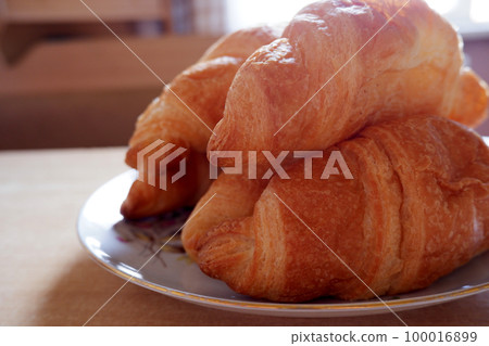 Croissants in a white plate on a wooden table 100016899
