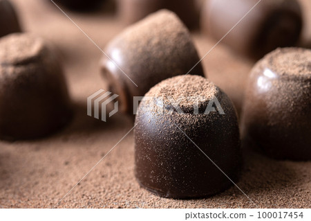Chocolate bonbons and cocoa powder background 100017454