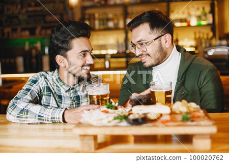 Indian friends celebrating in a pub with beer Indian friends celebrating in a pub with beer 100020762