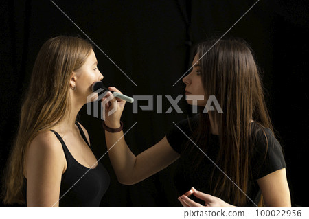 Process of making makeup. Make-up artist working with brush on model face. Portrait of young blonde woman in beauty saloon interior. Applying tone to skin. Process of making makeup. Make-up artist working with brush on model face. Portrait of young blonde woman in beauty saloon interior. Applying tone to skin. 100022956