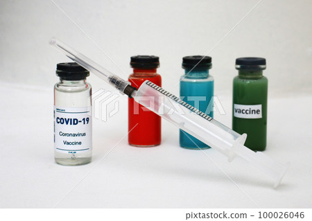 Four ampoules with vaccine and medicines and a syringe on a light background. 100026046