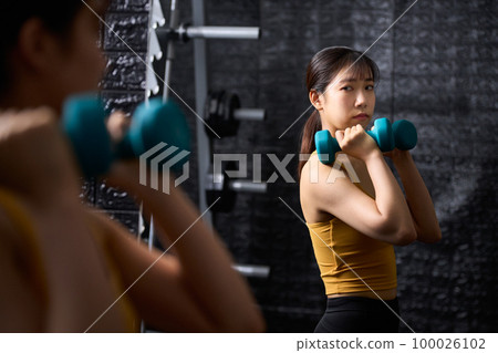 年輕女子在鏡子前用啞鈴訓練 100026102