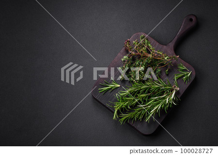 Sprigs of fresh green rosemary on a wooden cutting board 100028727