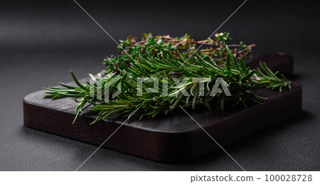 Sprigs of fresh green rosemary on a wooden cutting board Sprigs of fresh green rosemary on a wooden cutting board 100028728