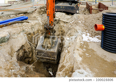 A hydraulic excavator digs a hole for the replacement of underground communication pipes 100028806