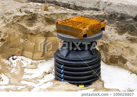 Installation of a new modern plastic rainwater drainage well with cast iron grate in the city street 100028807