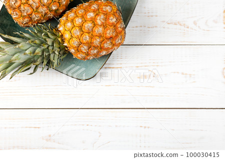 Juicy pineapples in a green plate on a white wooden background. Healthy, detox and dietary nutrition concept. 100030415
