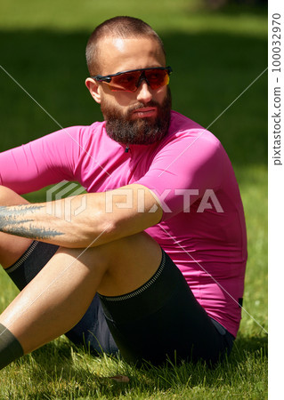 Portrait of a professional cyclist in sportswear, sits resting and enjoying the sun in the park, copyspace. The concept of an active and healthy lifestyle. Portrait of a professional cyclist in sportswear, sits resting and enjoying the sun in the park, copyspace. The concept of an active and healthy lifestyle. 100032970