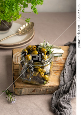Green and black olives mix, in a glass jar. Delicious, marinated olives.  100033920