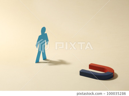 Magnet attracting paper person on beige background 100035286