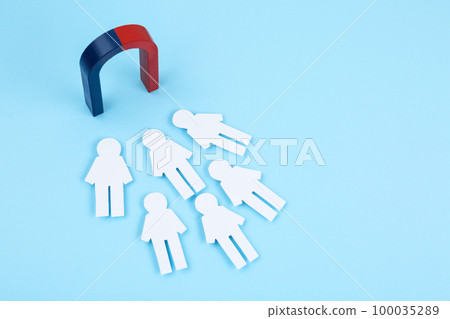 Magnet attracting paper people on light blue background 100035289