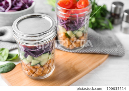 Healthy salad in glass jars on white table Healthy salad in glass jars on white table 100035514