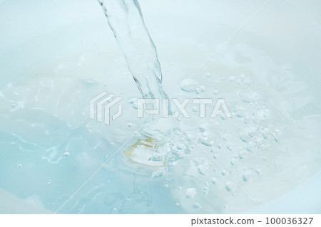 a jet of water pours into a container of water.  100036327