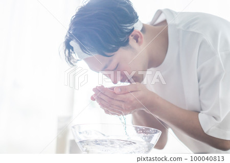 A young man wearing a hair band and washing his face A young man wearing a hair band and washing his face 100040813