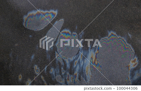 Iridescent spot of gasoline. Petrol on the asphalt a big polluted puddle water. A rainbow slick of gasoline Iridescent spot of gasoline. Petrol on the asphalt a big polluted puddle water. A rainbow slick of gasoline 100044306