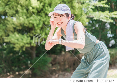 一位女士在公園裡邊看手錶邊鍛煉、訓練和散步(時間、時間、醫療保健) 一位女士在公園裡邊看手錶邊鍛煉、訓練和散步(時間、時間、醫療保健) 100048487