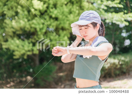 一位女士在公園裡邊看手錶邊鍛煉、訓練和散步(時間、時間、醫療保健) 一位女士在公園裡邊看手錶邊鍛煉、訓練和散步(時間、時間、醫療保健) 100048488