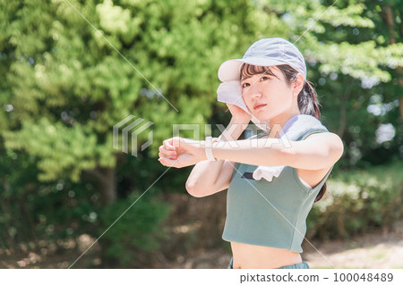 一位女士在公園裡邊看手錶邊鍛煉、訓練和散步(時間、時間、醫療保健) 一位女士在公園裡邊看手錶邊鍛煉、訓練和散步(時間、時間、醫療保健) 100048489