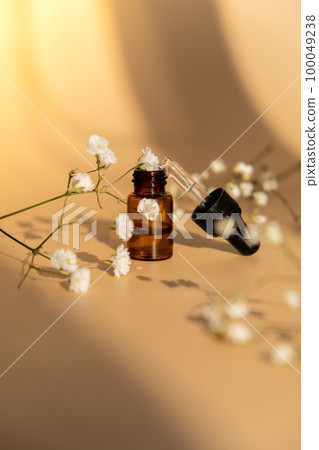 Small bottle of serum on neutral beige background. Beauty pipette dropper with Gypsophila or baby's breath white flowers. Glass dropper of cosmetic oil and dried flowers and herbs. Natural organic Small bottle of serum on neutral beige background. Beauty pipette dropper with Gypsophila or baby's breath white flowers. Glass dropper of cosmetic oil and dried flowers and herbs. Natural organic 100049238