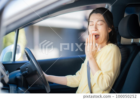 Middle woman yawning while driving 100050252
