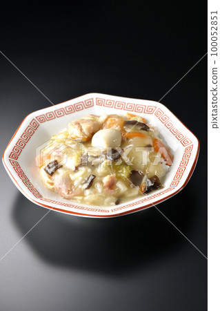 A Chinese rice bowl served on an octagonal Chinese dish is photographed against a black background. 100052851