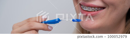 Caucasian woman cleaning her teeth with braces using a brush. Widescreen. Caucasian woman cleaning her teeth with braces using a brush. Widescreen. 100052979
