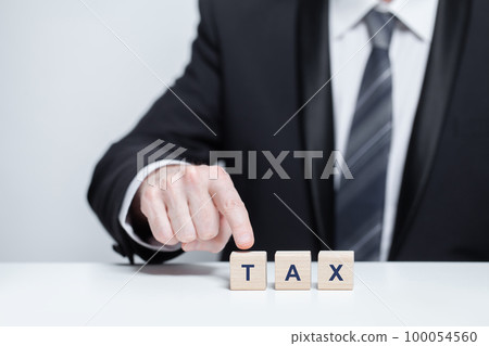 Wooden cubes with word tax. Businessman in suit pointing on block.  100054560