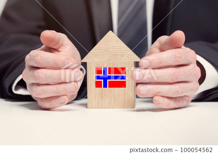 Businessman hand holding wooden home model with Norvegian flag. insurance and property concepts 100054562